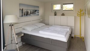 A bedroom with a bed, a lamp, a coat rack, a window, and a painting on the wall. - Fan of Ibiza "style"? Then we can assure you that you will feel at home here! Via the shell path and (Burgh-Haamstede)