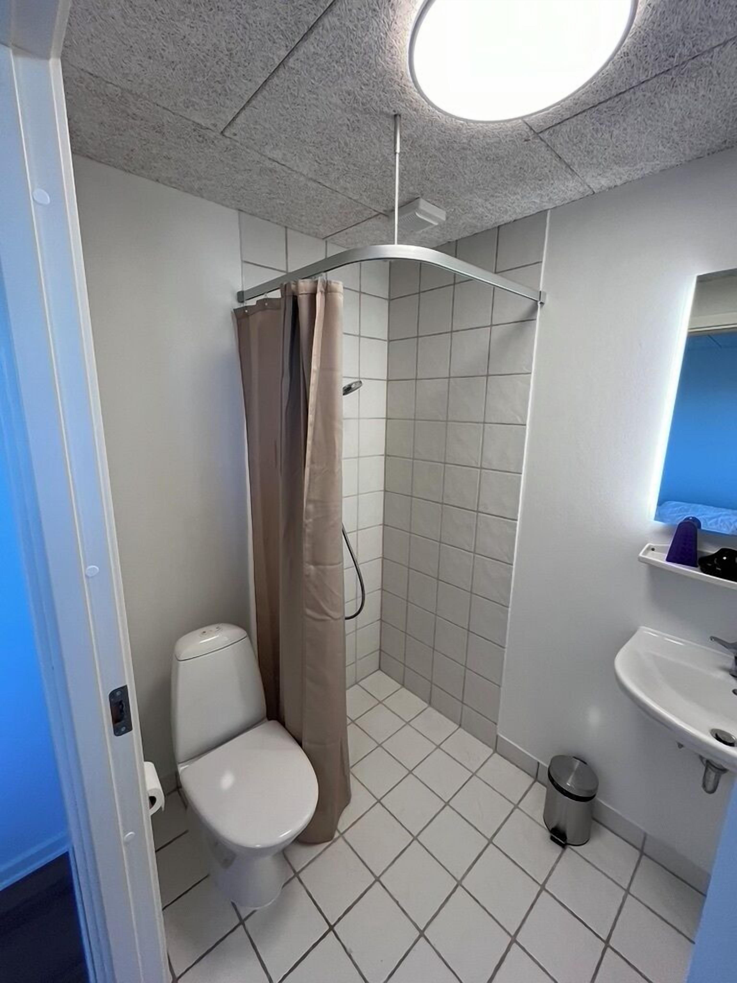 Un baño pequeño con inodoro, ducha y lavamanos.