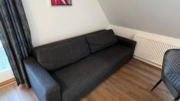 En moderne stue med en mørkegrå sofa, et billede på væggen og en radiator.