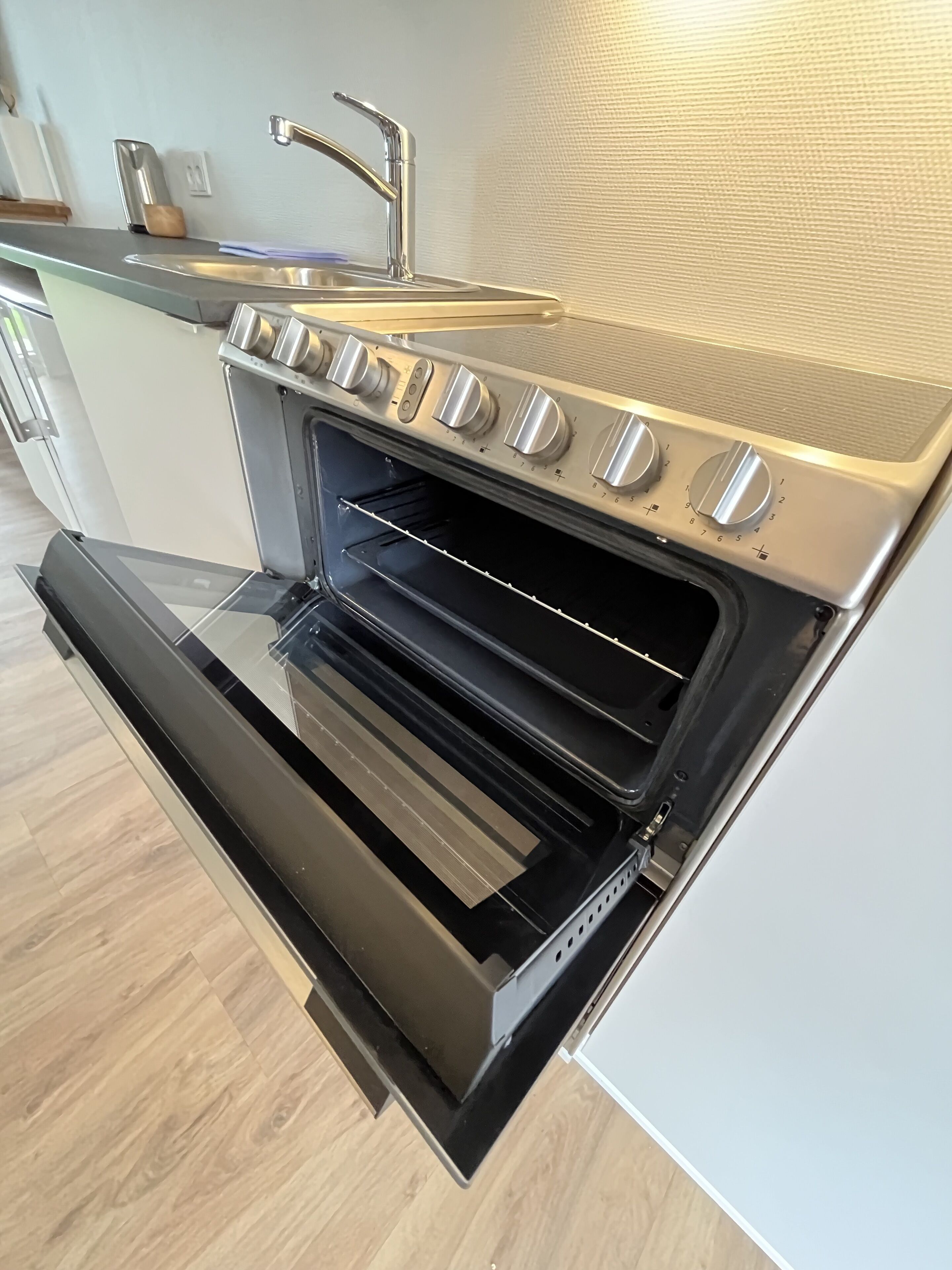 A modern kitchen with a built-in oven and a stainless steel sink.