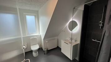 Une salle de bain moderne équipée de toilettes, d’un lavabo et d’une douche.