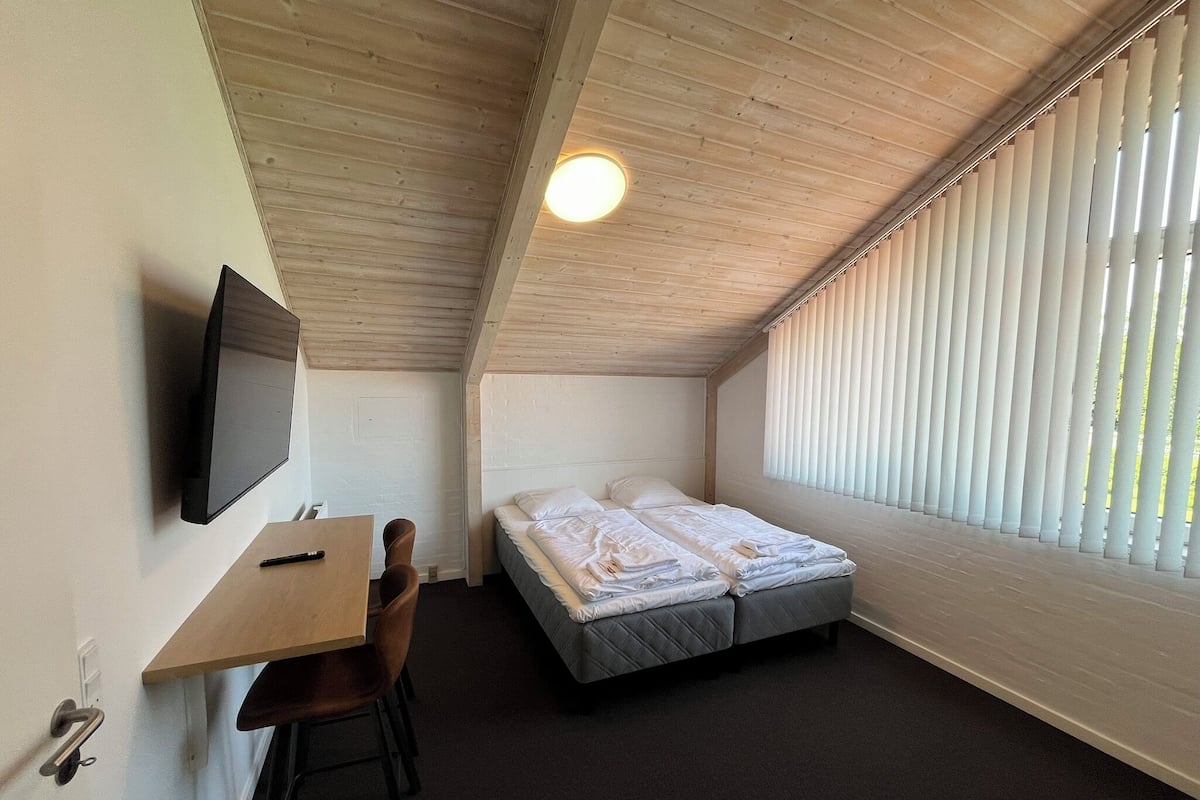 A small, cozy room with a bed, a desk, and a TV.
