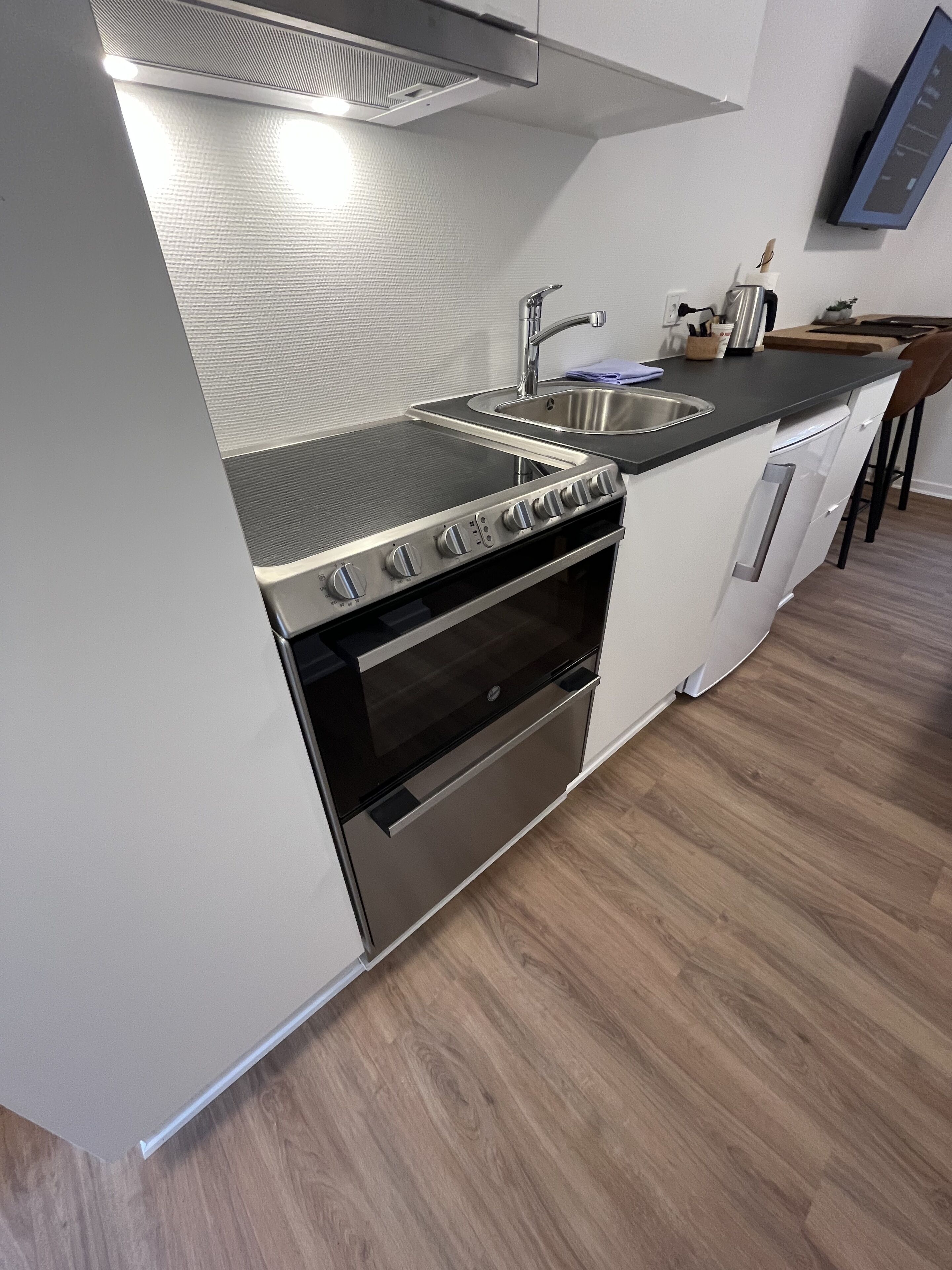 A modern kitchen with a stainless steel range hood, double oven, and a sink.