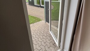 Ein modernes Gebäude mit rotem Dach, großen Fenstern und einem gepflasterten Eingangsbereich.