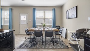 A dining area with a table set for four, a high chair, and a kitchen area with a dishwasher. - Near IAH Houston Home | Yard BBQ Games Wi-Fi Pets (Houston)