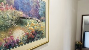 Un tableau encadré représentant un pont enjambant une étendue d’eau, avec des fleurs aux couleurs vives sur les rives.