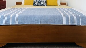 Ein Schlafzimmer mit einem hölzernen Bett, einem runden Spiegel und einer weißen Klimaanlage an der Wand.