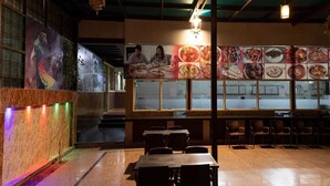 A restaurant with a mural of a bird, tables, chairs, and a menu board. - Home Stay Green View Doon (Dehradun)