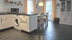 Une cuisine moderne équipée d’un lave-linge, d’un four à micro-ondes et d’un coin repas avec des chaises et une table.