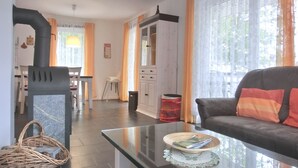 Un salon avec une table basse en verre, un canapé, une cheminée et, au fond, un coin repas.