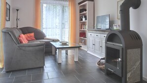 Un salon comprenant un canapé, une table basse, une cheminée, un téléviseur et une bibliothèque.