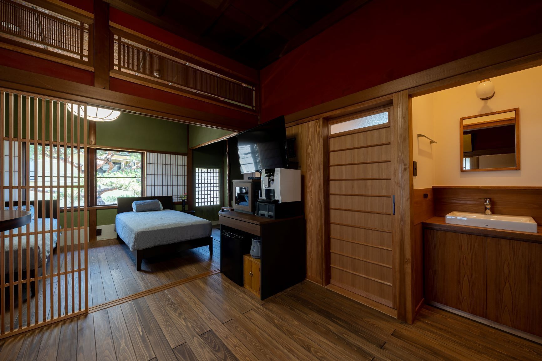 Een traditionele Japanse kamer met een bed, een bureau, een wastafel en een schuifdeur.