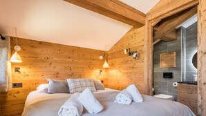 Um quarto aconchegante de madeira, com uma cama, duas luzes fixadas na parede e um armário de madeira.