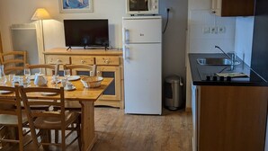 Eine kompakte Küche mit Essbereich, ausgestattet mit einer Mikrowelle, einem Kühlschrank und einem kleinen Spülbecken.