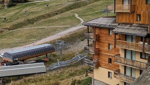 Ein Holzbalkongebäude mit Skilift und einem Weg in einer hügeligen Gegend.