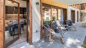 Un área de estar moderna al aire libre con tumbonas de madera y una mesa de comedor.