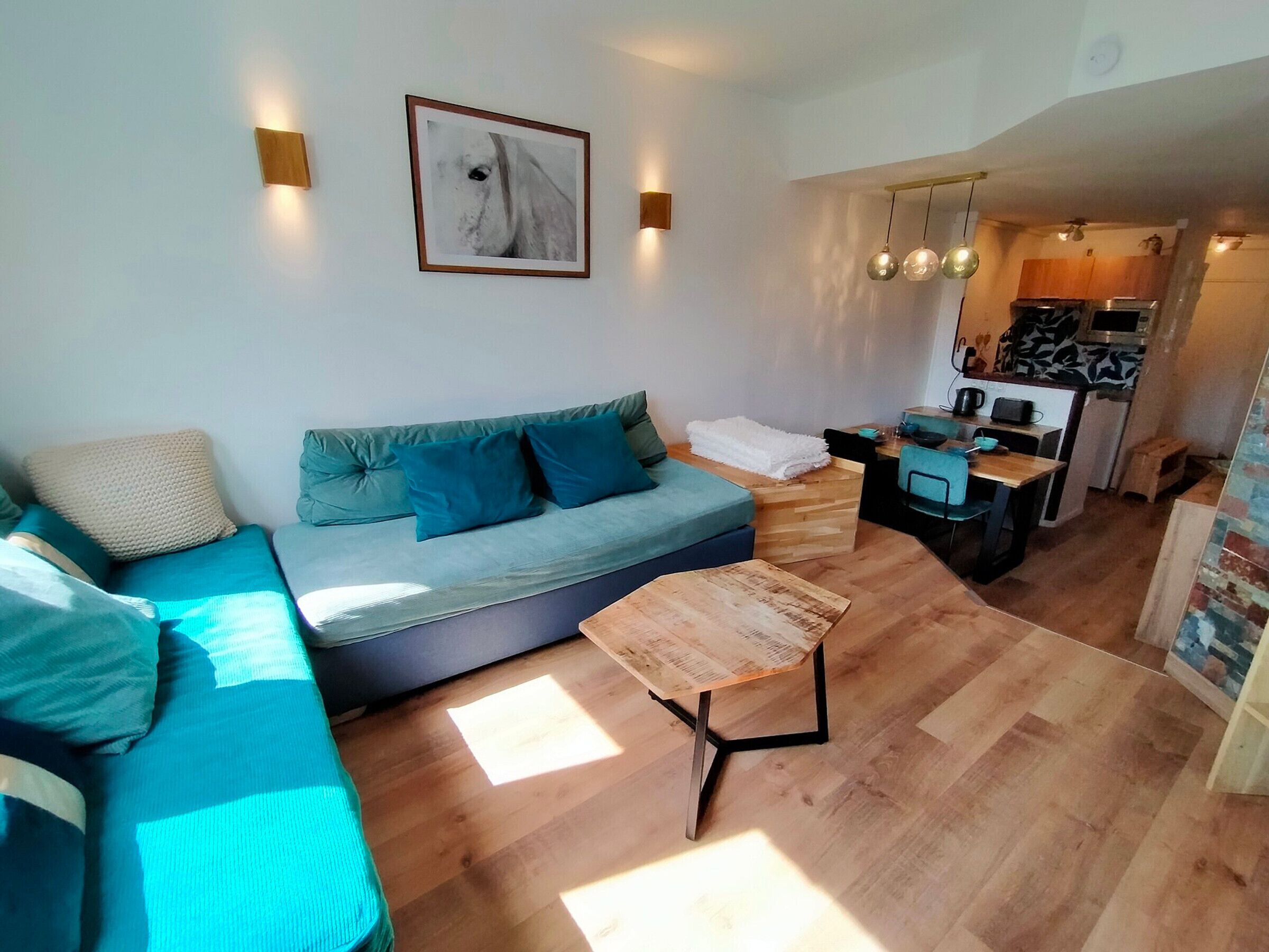 A modern living room with a sofa, a coffee table, and a kitchen area visible in the background.