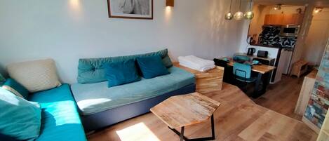 A modern living room with a sofa, a coffee table, and a kitchen area visible in the background.
