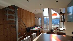 A modern kitchen with a wooden interior, a dining area with a table and chairs, and a staircase leading to an upper level. - Renovated triplex apartment Avoriaz, 6 pax, premium amenities (Avoriaz)