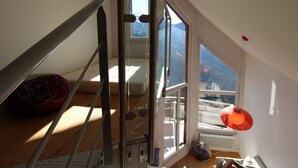A high-ceilinged room with a large window, a staircase, and a bed. - Renovated triplex apartment Avoriaz, 6 pax, premium amenities (Avoriaz)