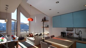 A modern kitchen with a dining area, large windows, and a view of mountains. - Renovated triplex apartment Avoriaz, 6 pax, premium amenities (Avoriaz)