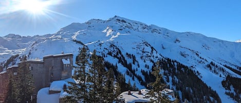 A snow-covered mountain with a clear sky and a building with a snow-covered roof.