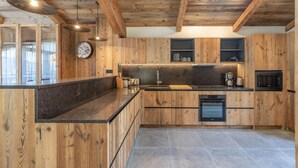 Une cuisine moderne avec des meubles en bois, un plan de travail noir et un four encastré.