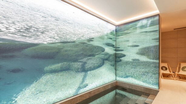 Une salle de bain moderne avec un grand mur de verre offrant une vue dégagée sur le monde sous-marin.