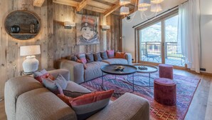 Un salon chaleureux avec un plafond en bois, un grand tableau et une vue sur l’extérieur.