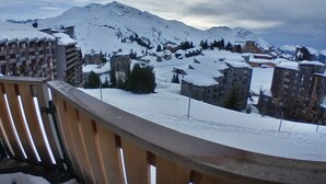 Cidade montanhosa coberta de neve, com edifícios e uma varanda de madeira.