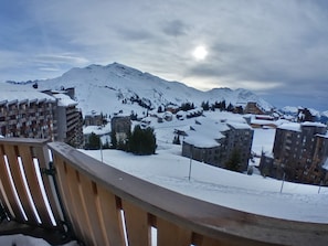 Une ville de montagne enneigée, avec des bâtiments et un balcon en bois.