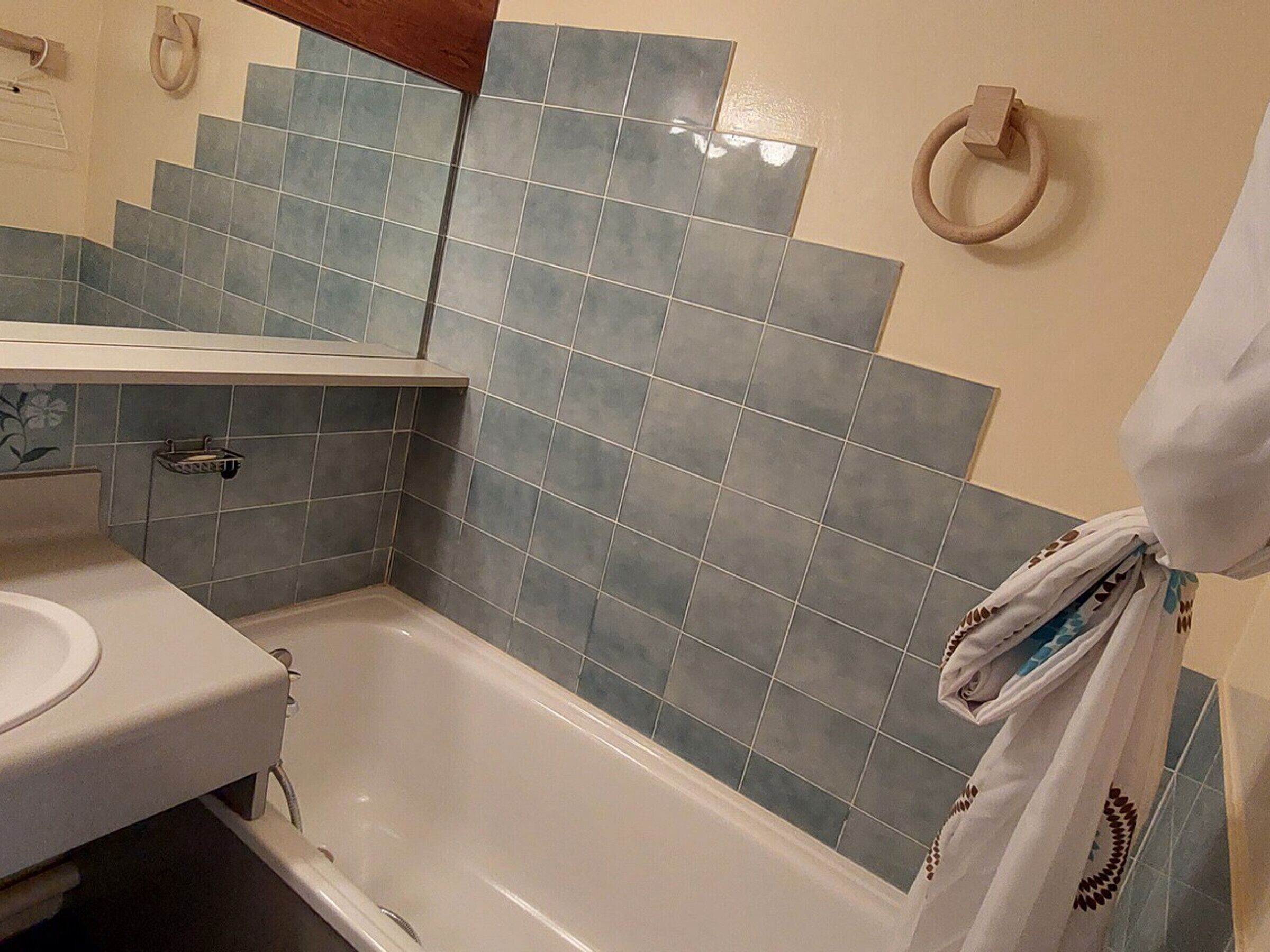 A bathroom with a bathtub, a sink, and a towel rack.