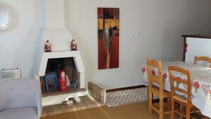 A living room with a fireplace, a dining table with chairs, and a small armchair.
