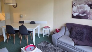 En moderne stue med en grå sofa, et spisebord med stole, et lille sofabord og et stort blomstermotiv på væggen.