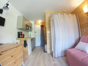 A compact room with a kitchenette, a wooden desk, a bed, and a shower curtain. - Renovated Studio for 4, balcony, ski-in/ski-out (Avoriaz)