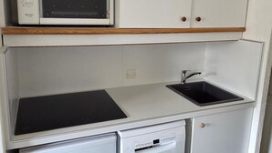 A compact kitchenette with a microwave, a sink, and a dishwasher.