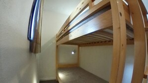 A bunk bed room with a slanted ceiling and a small window.