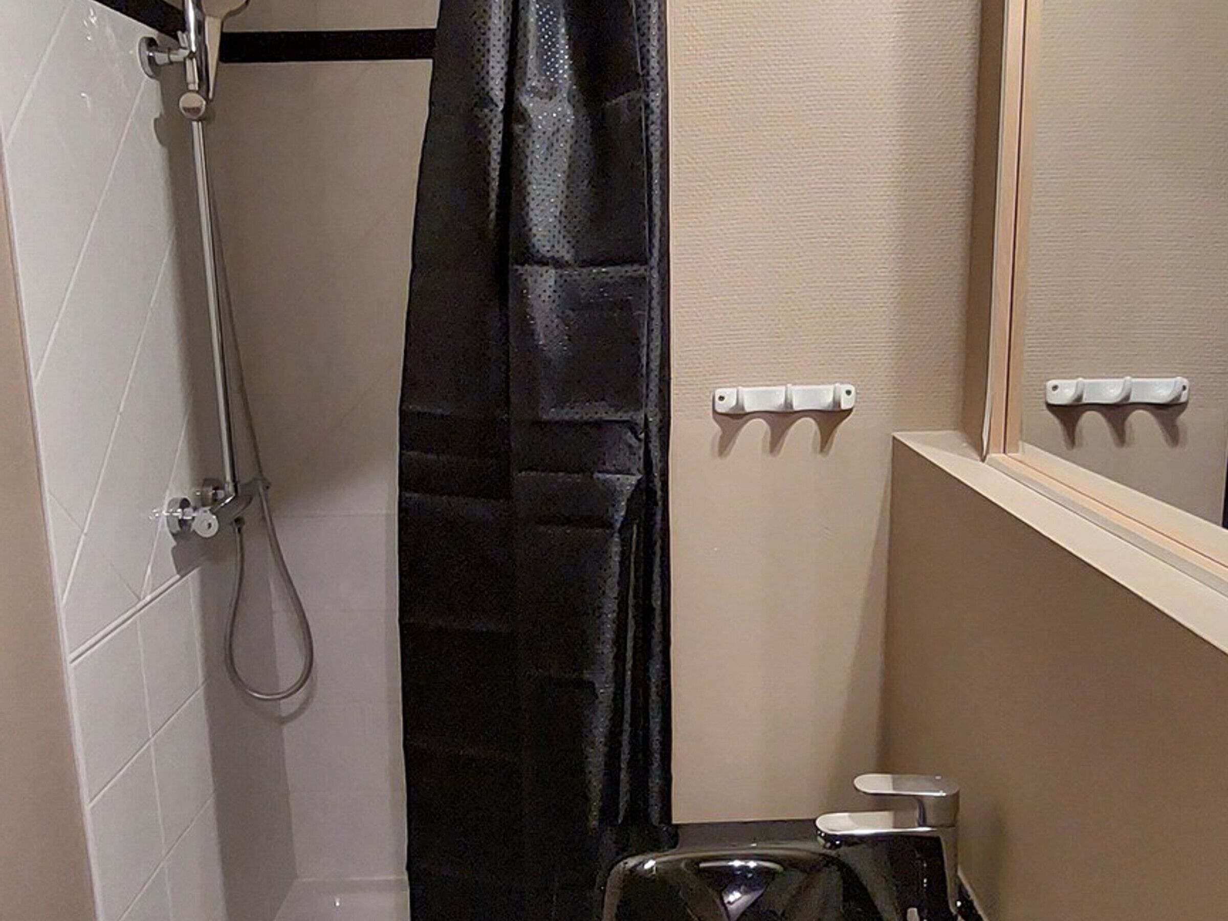 A bathroom with a shower, a toilet, and a mirror.