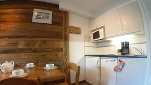 A compact kitchen with a wooden accent wall, a microwave, a coffee maker, and a small refrigerator. - Charming 2-Room Cabin for 6 in Avoriaz Center (Avoriaz)