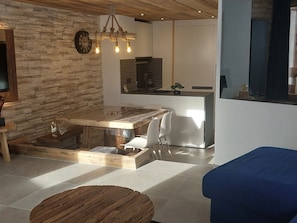 Uma cozinha moderna com ilha central, piso de madeira e parede de pedra.