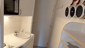 A compact bathroom with a white sink, a small toilet, and a microwave.