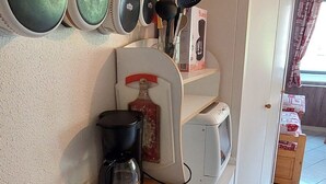 A kitchen with a coffee maker, toaster, and a wine bottle on a shelf.