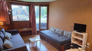 A cozy room with a bed, a sofa, a small table, and a TV.