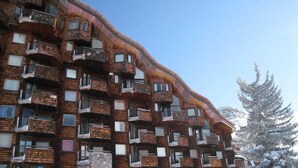 A multi-story building with numerous balconies, a stone base, and a snowy environment.