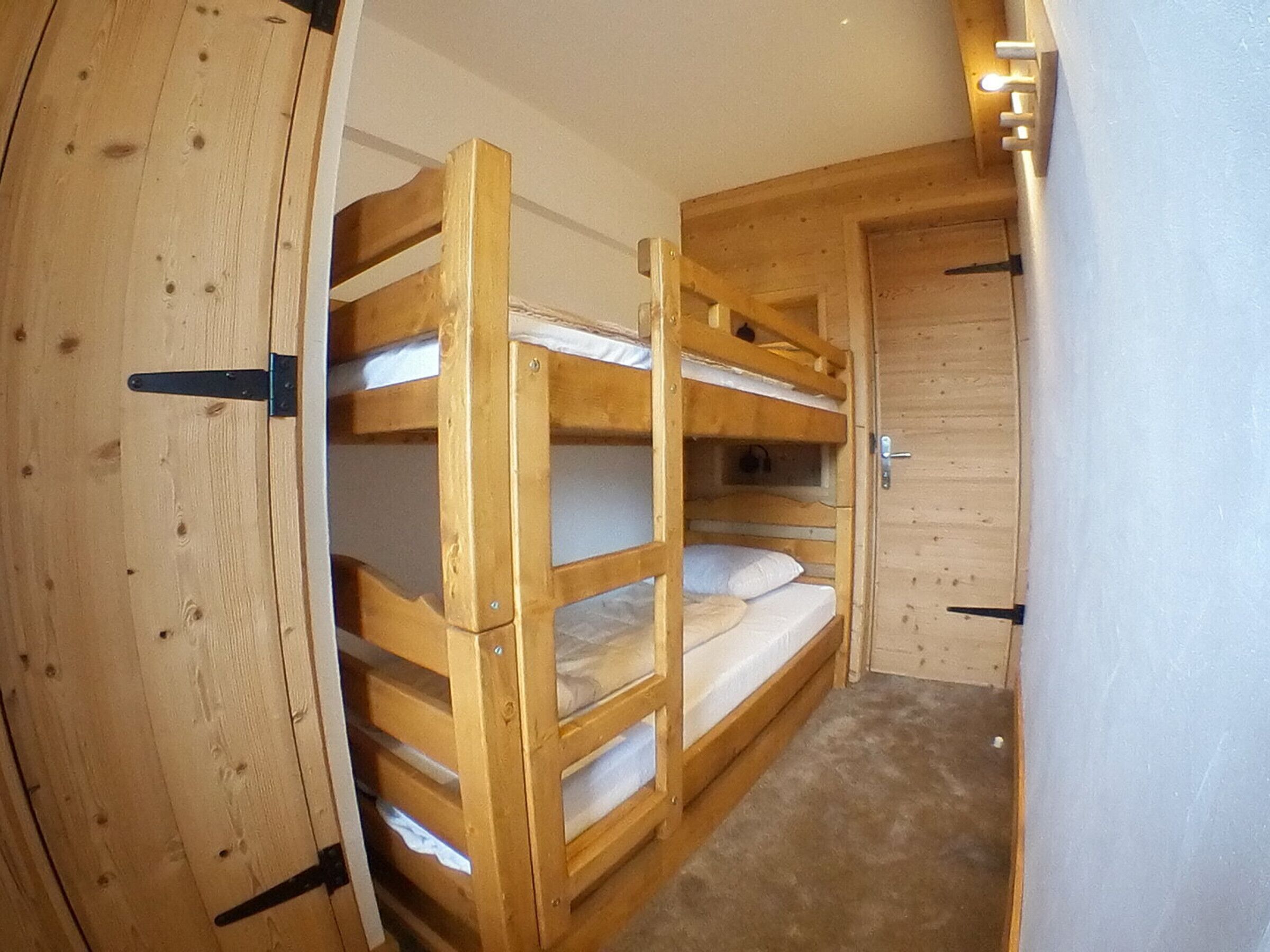 A bunk bed room with a wooden door and a light switch on the wall.