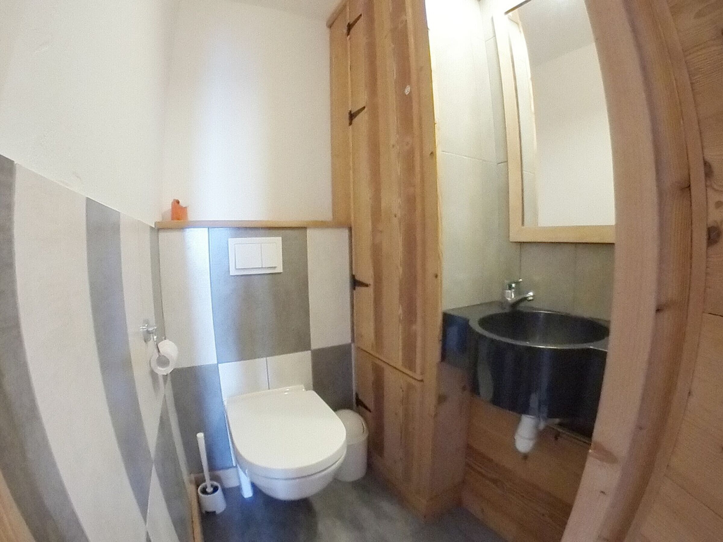 A small bathroom with a toilet, a sink, and a mirror.