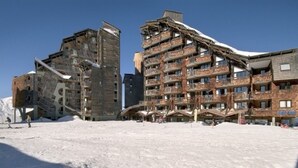 Et skisportssted dækket af sne med høje bygninger, altaner og skiheiser.