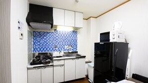 A compact kitchen with white cabinets, a black refrigerator, a microwave, and a sink.