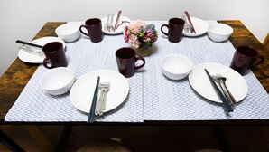 A dining table set with plates, bowls, cups, and cutlery.