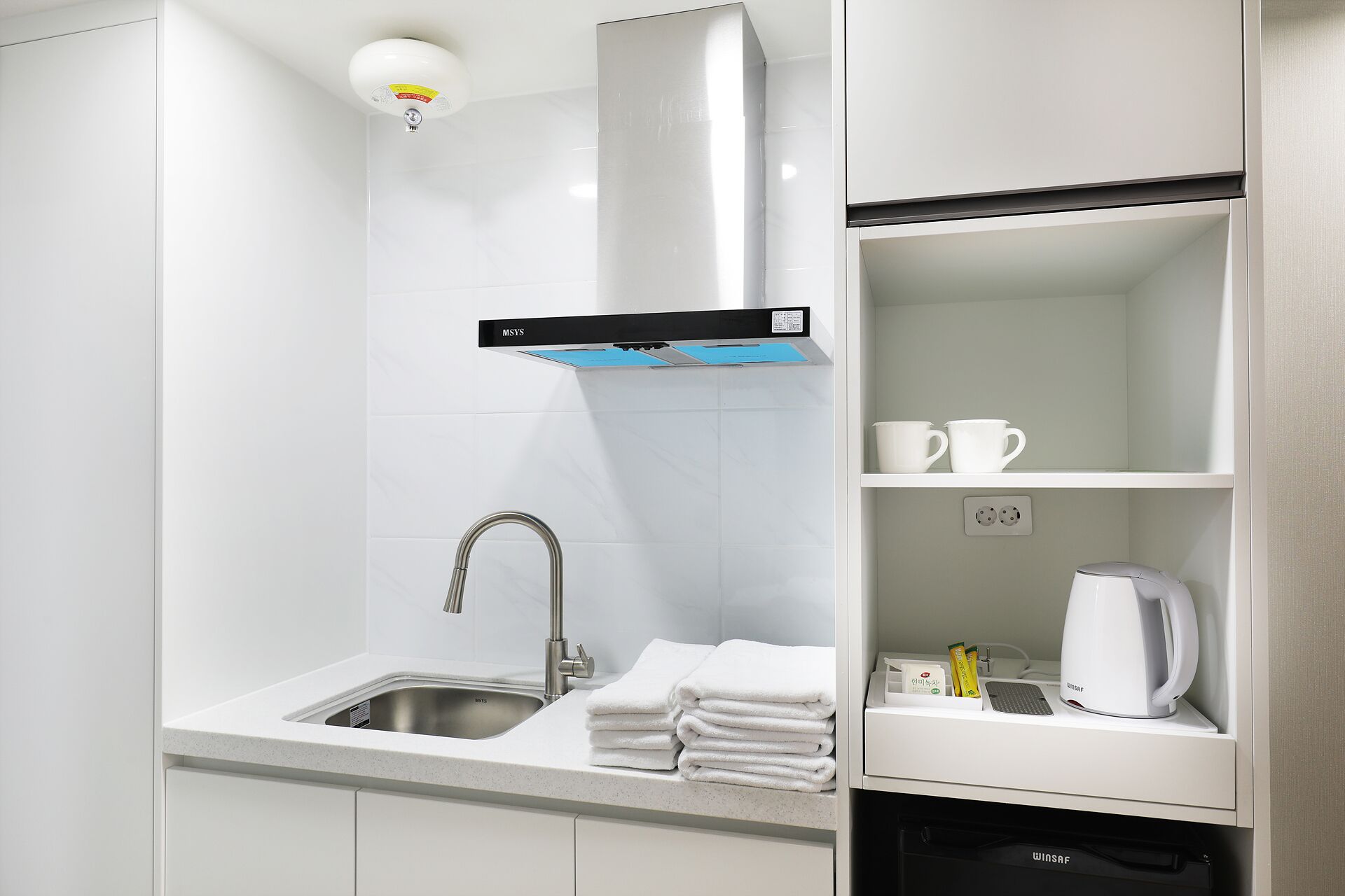 Una cocina moderna con un lavamanos de acero inoxidable, una estufa integrada y una cafetera sobre la encimera.